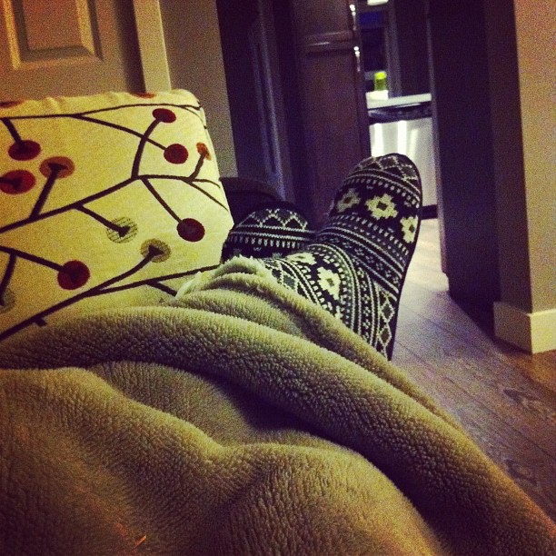 a persons feet resting on a couch covered in a blanket