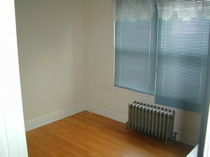 an empty living room with a heater and hardwood floors