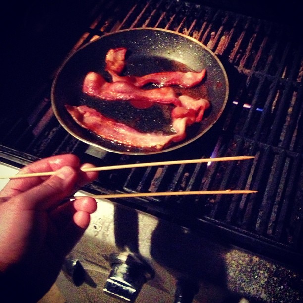 bacon and wooden sticks cooking on a grill