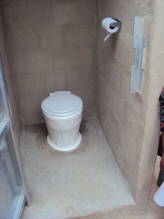 a small white toilet with no lid in the corner of a bathroom