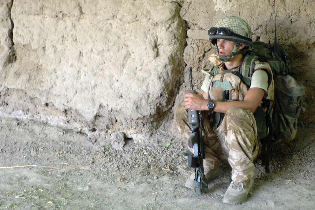 a soldier holding a rifle next to a rock