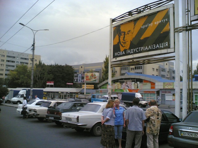 people walking down the street with cars and billboard in background