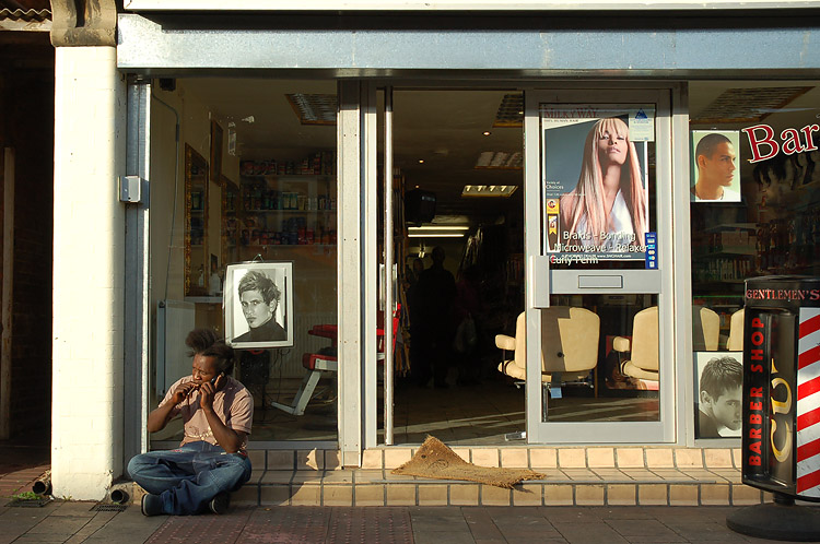 a man sitting on the sidewalk talking on a cell phone