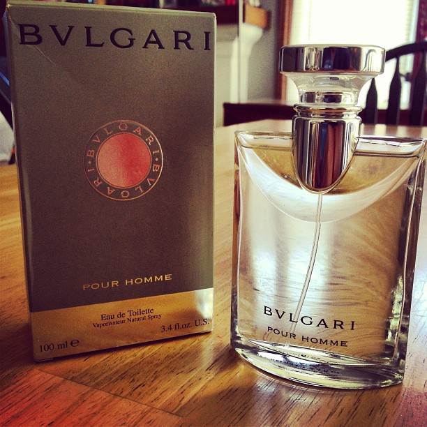an open box and a bottle of bvlgari perfume on a wooden table