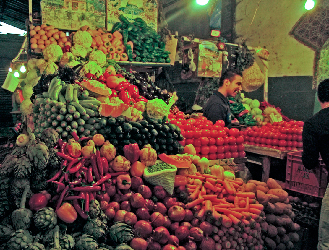 a couple of people looking at a bunch of produce in a market