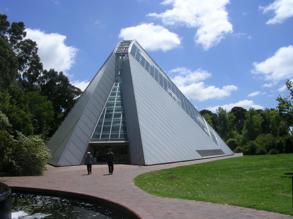 a triangular pyramid in a grassy area near a pond