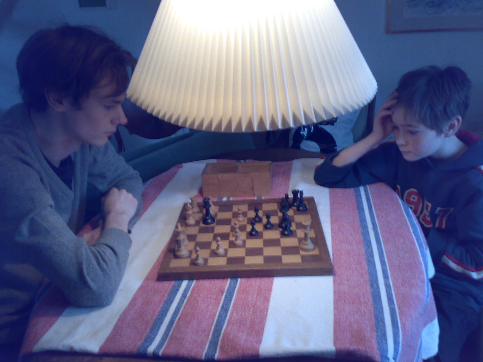 two boys sitting at a table and playing chess