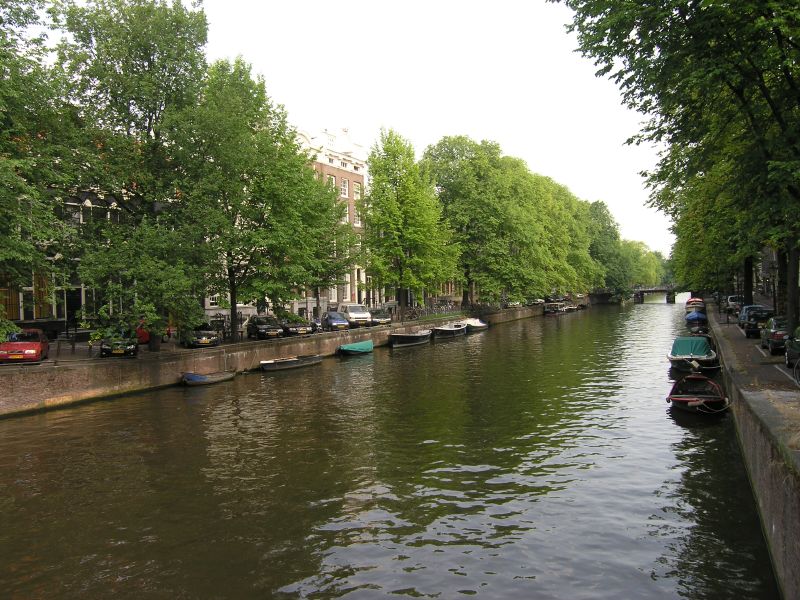 a canal filled with boats floating along side of green trees