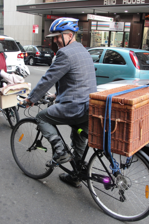 an older man in a hat is riding a bike with a wicker basket