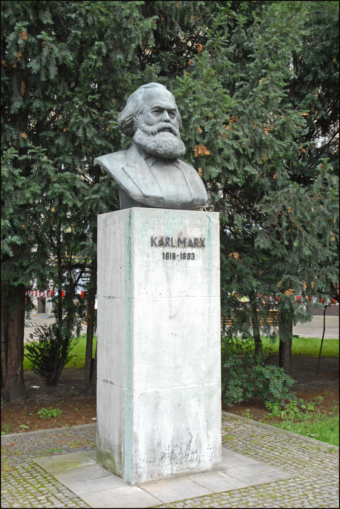 the bust of a man with long hair, wearing a suit and a beard