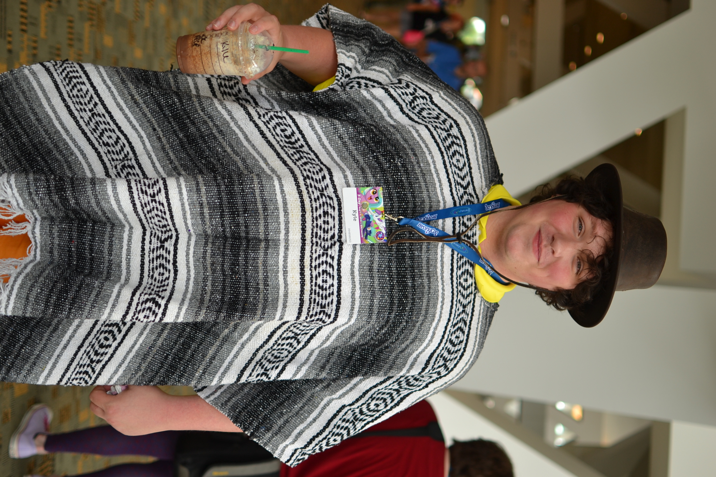 a woman wearing a colorful ponchee holding a drink