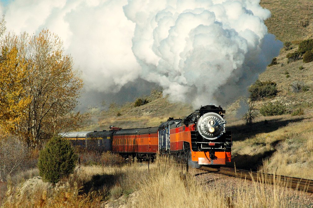 a steam train traveling on tracks in the wilderness