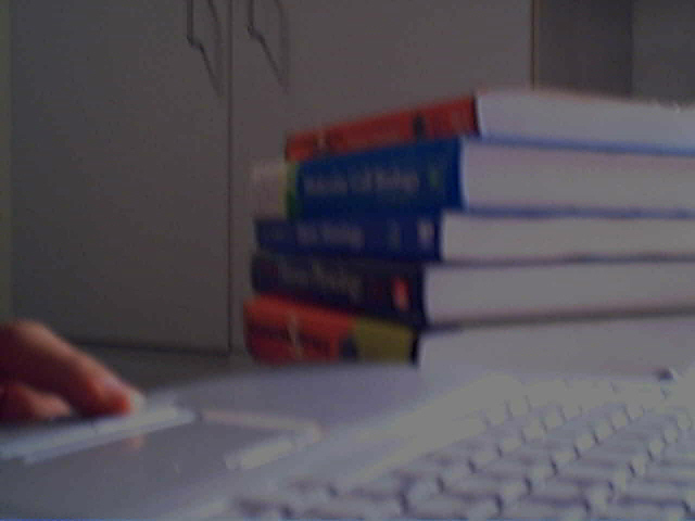 a stack of books is sitting on a table with the computer in front
