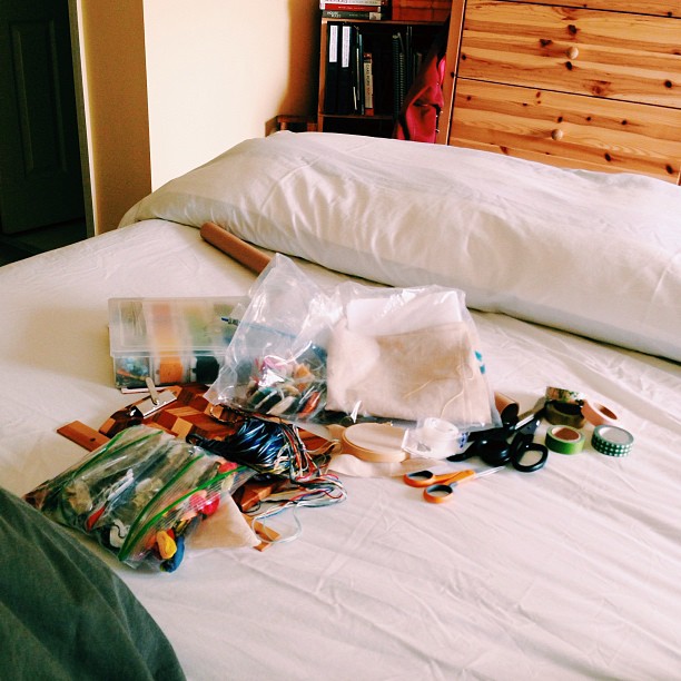 clothes, crafting supplies and yarn on a white bed