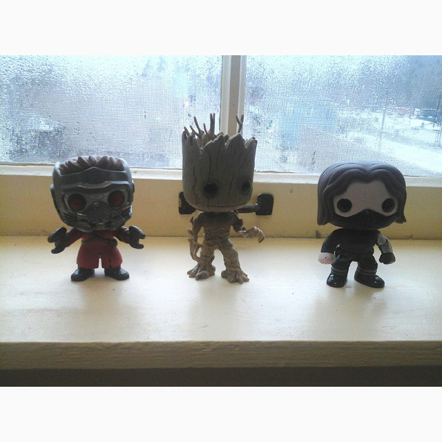 three little action figures sitting on a window sill