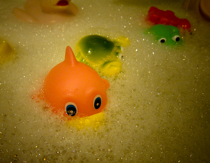 the bathtub features rubber ducks and plastic orange fish