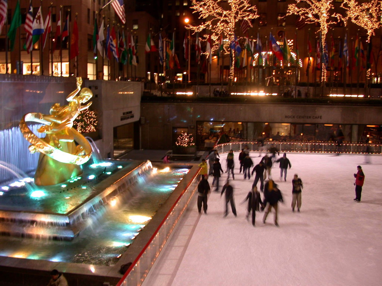 people ice skating around in an ice rink near several flags