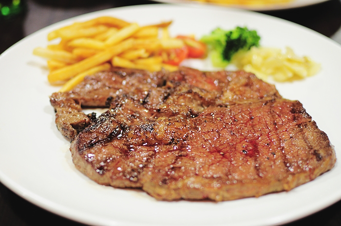 a large steak and french fries sitting on a plate
