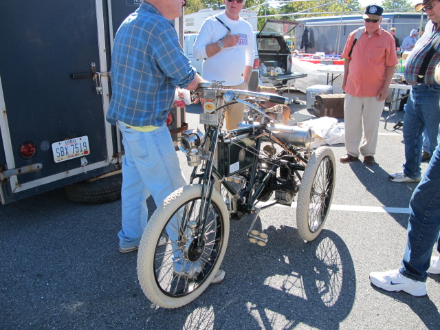 four men stand around a parked motorcycle that is being unfurled