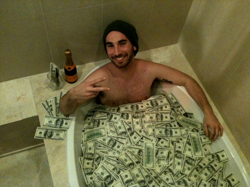 a man sitting in a tub with money all over it