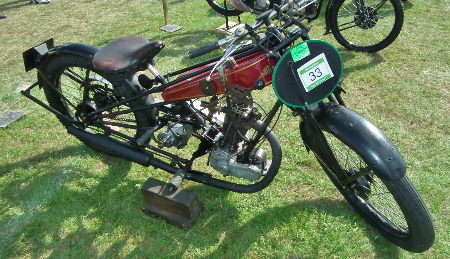 a motorcycle sits in the grass, with other motorcycles behind it
