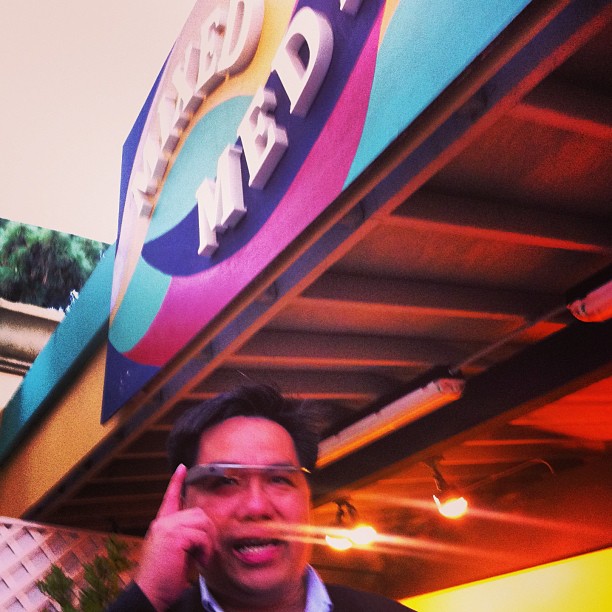 a man standing under a sign talking on a cell phone