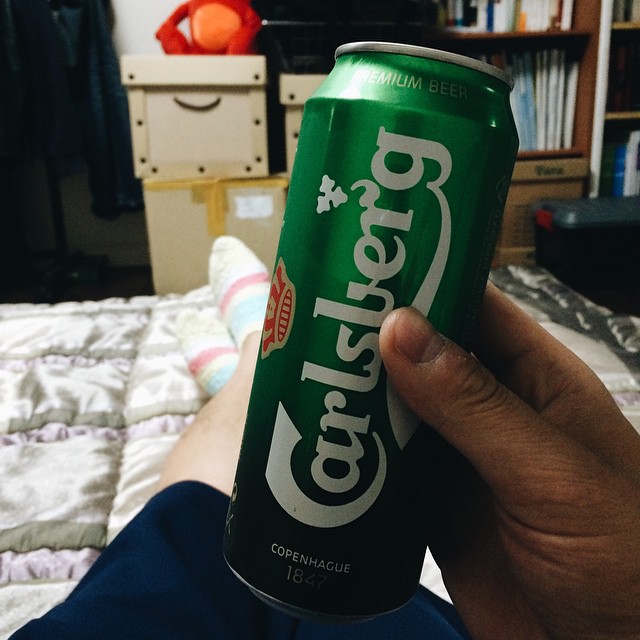 person holding up a can of beer in bed