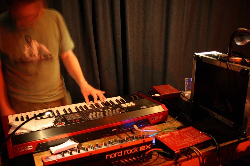 two hands on musical keyboard and various electronic equipment