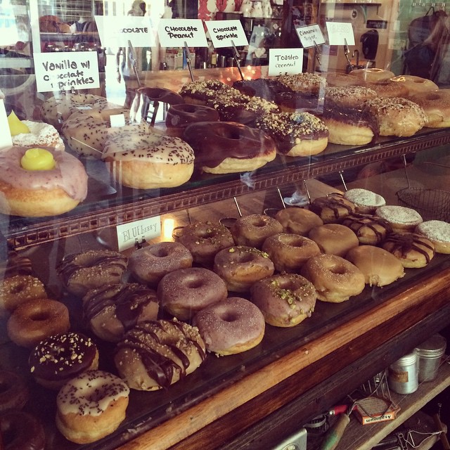 doughnuts are lined up in the glass of a shop