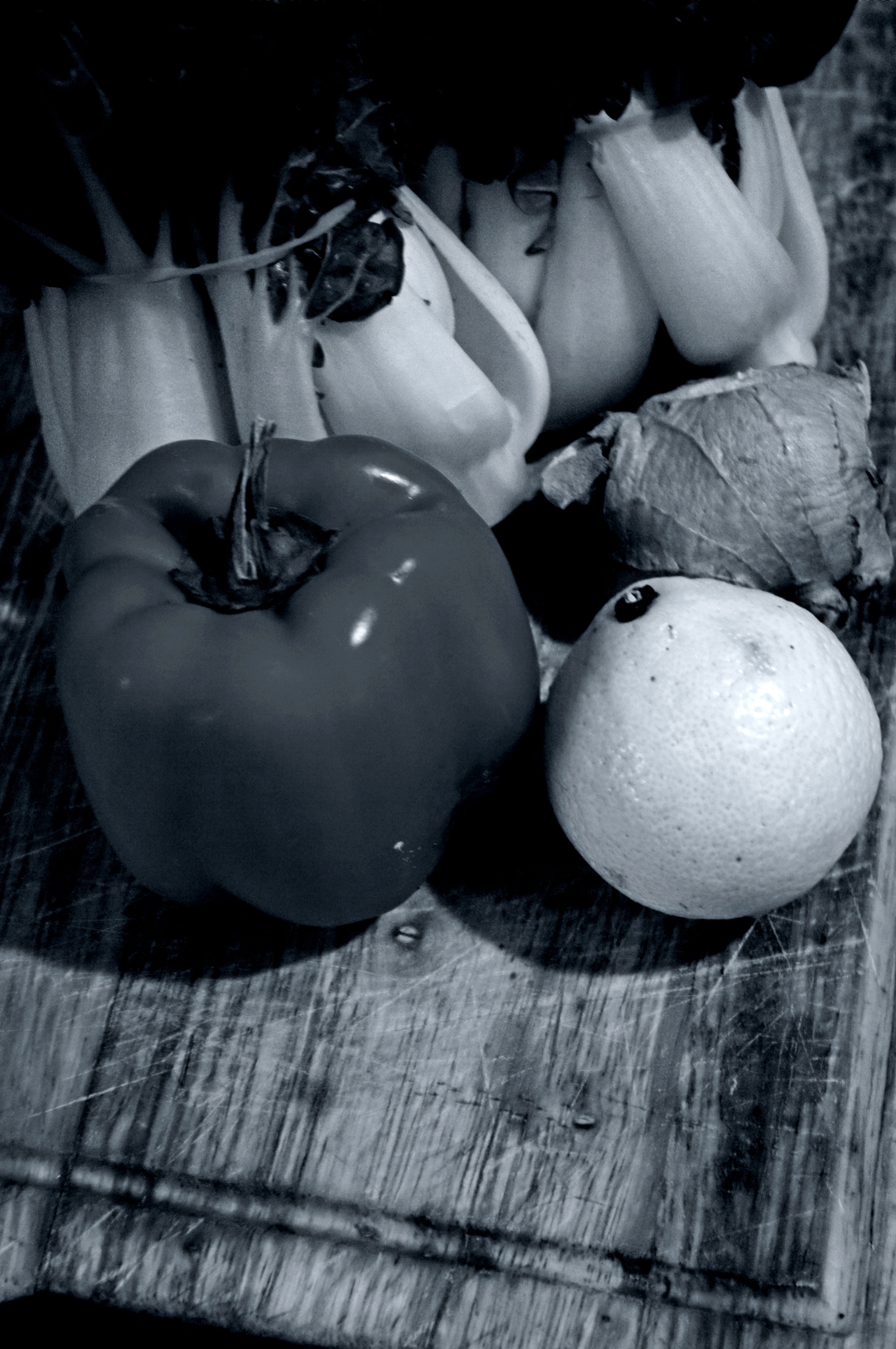 black and white po of an apple, a lemon, ginger, and other produce on a wooden table