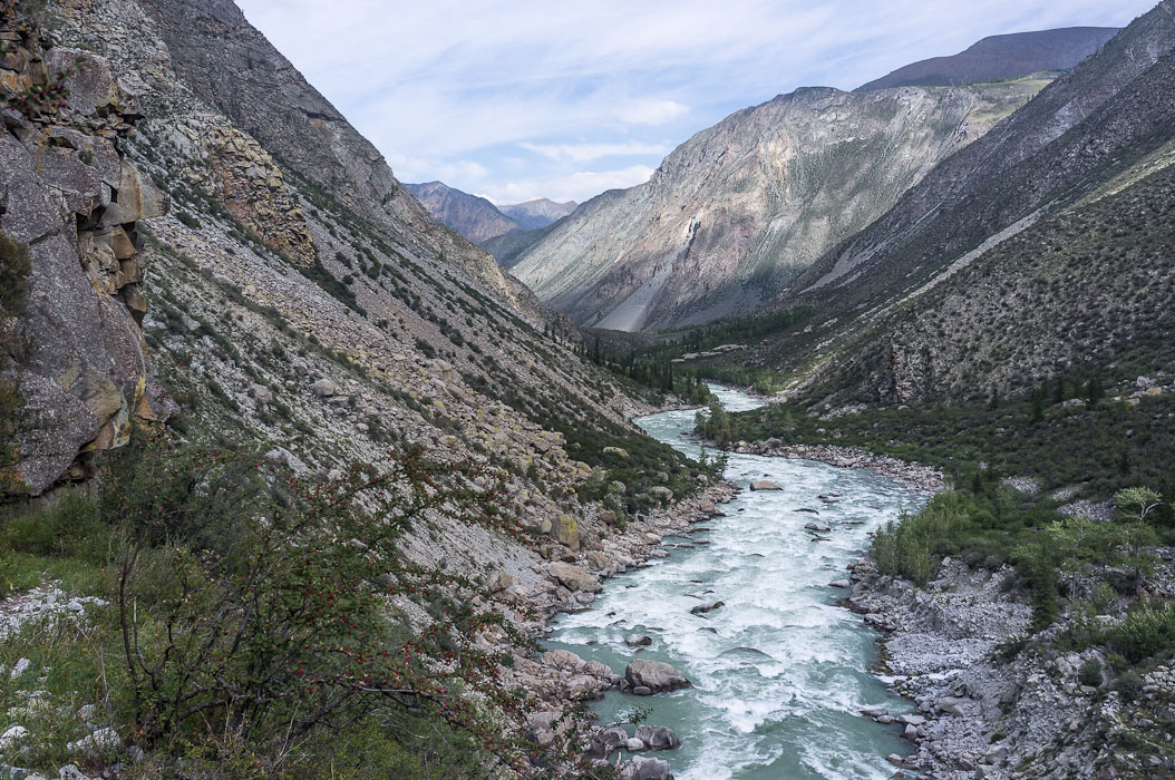 river surrounded by mountain ranges surrounded by grass and rock