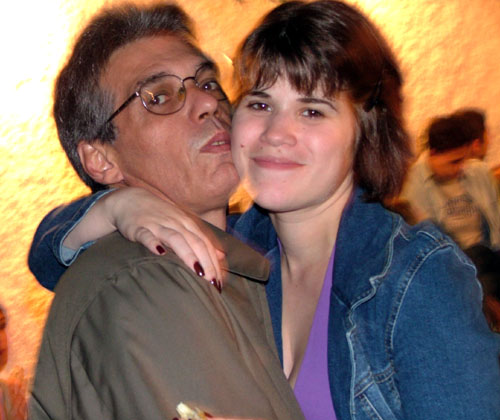 a woman hugging a man who is wearing glasses