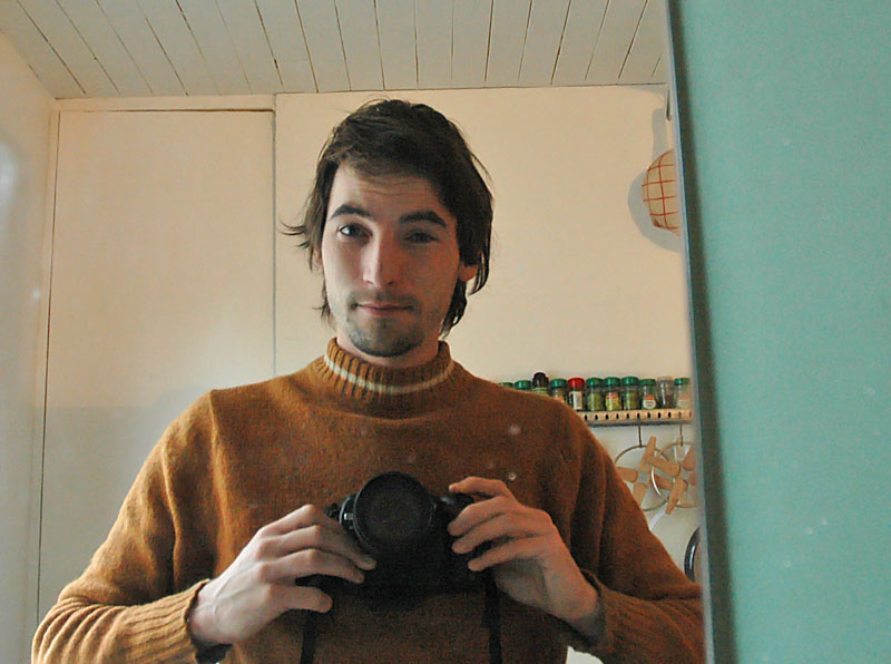 a man with long hair is standing in front of the mirror taking a picture