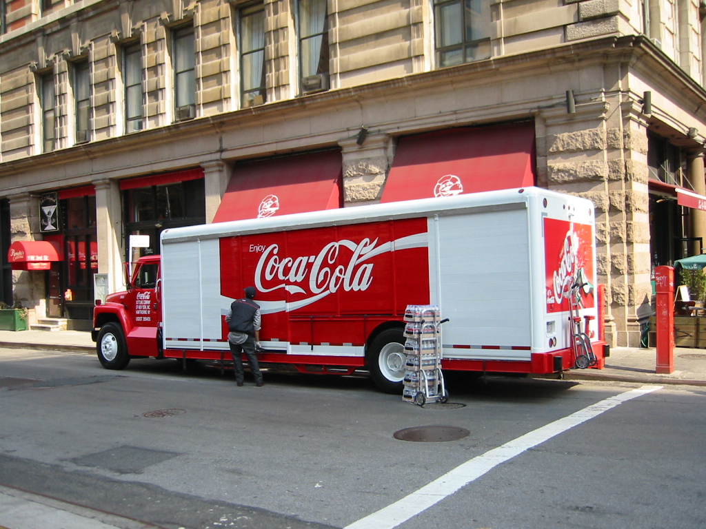 a person working on a coke - cola truck on a street