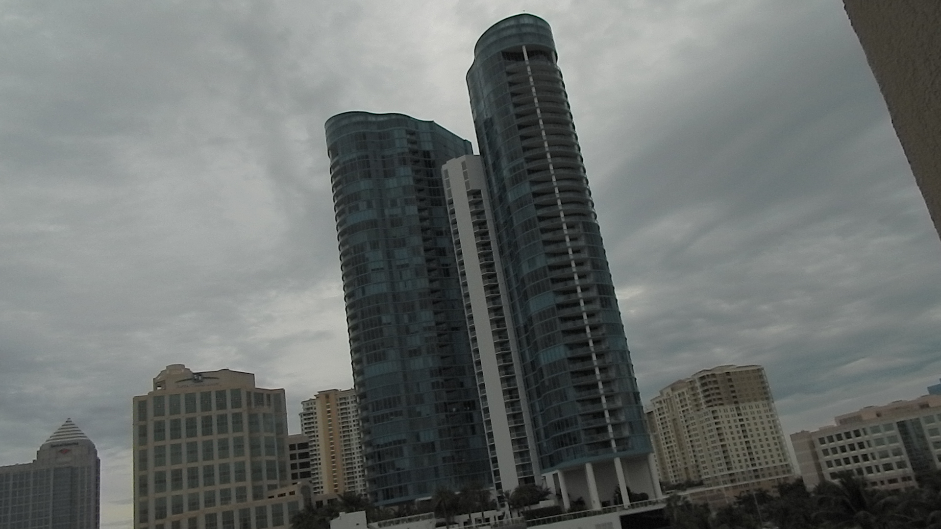 three high rise buildings under cloudy skies in a city