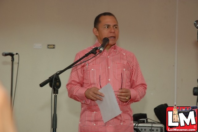 man in red striped shirt making an address for microphone