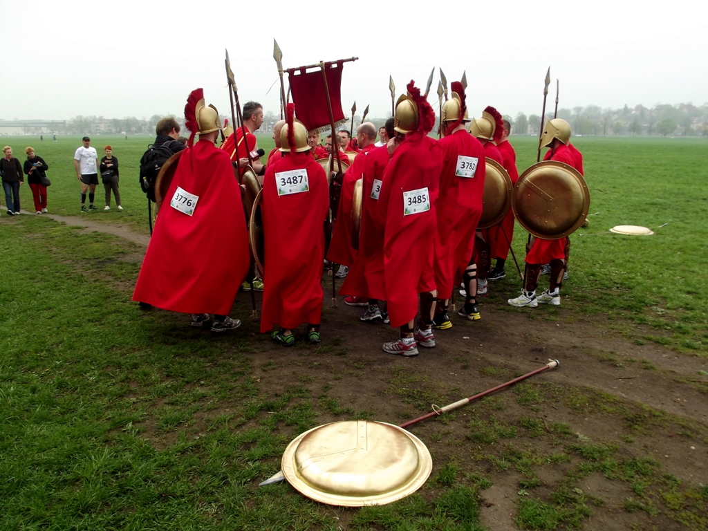 group of people dressed in red with gold shields and roman armor