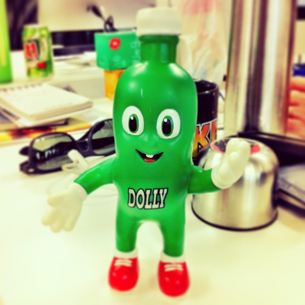 green toy with words dolly on it in front of a cluttered desk