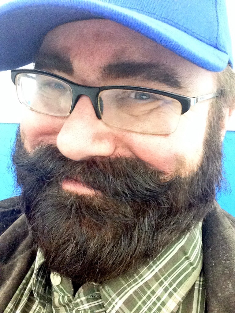 a man with glasses and a hat has a big beard