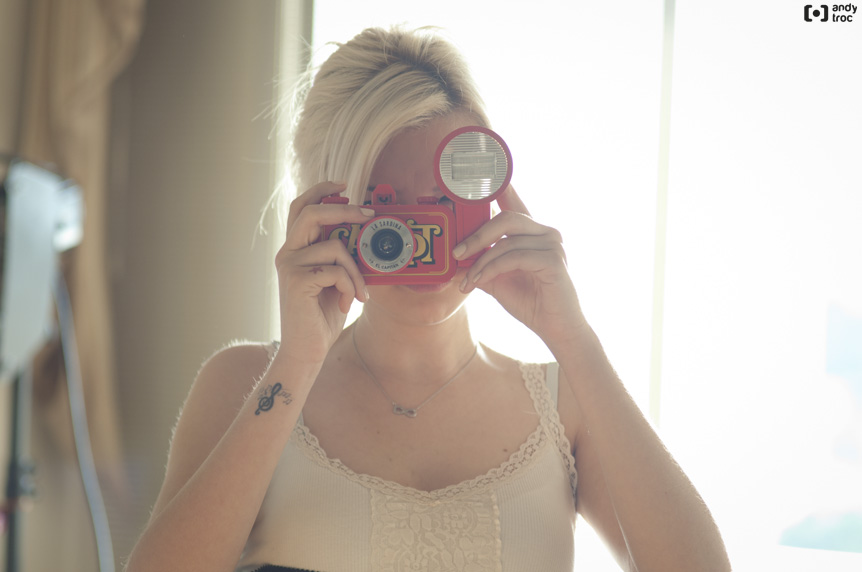 a girl with short hair is holding up a red camera