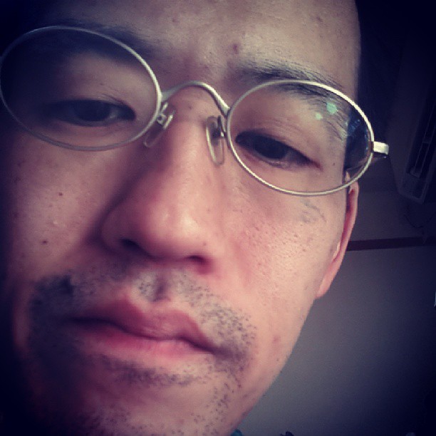 an asian man in large circular glasses making faces