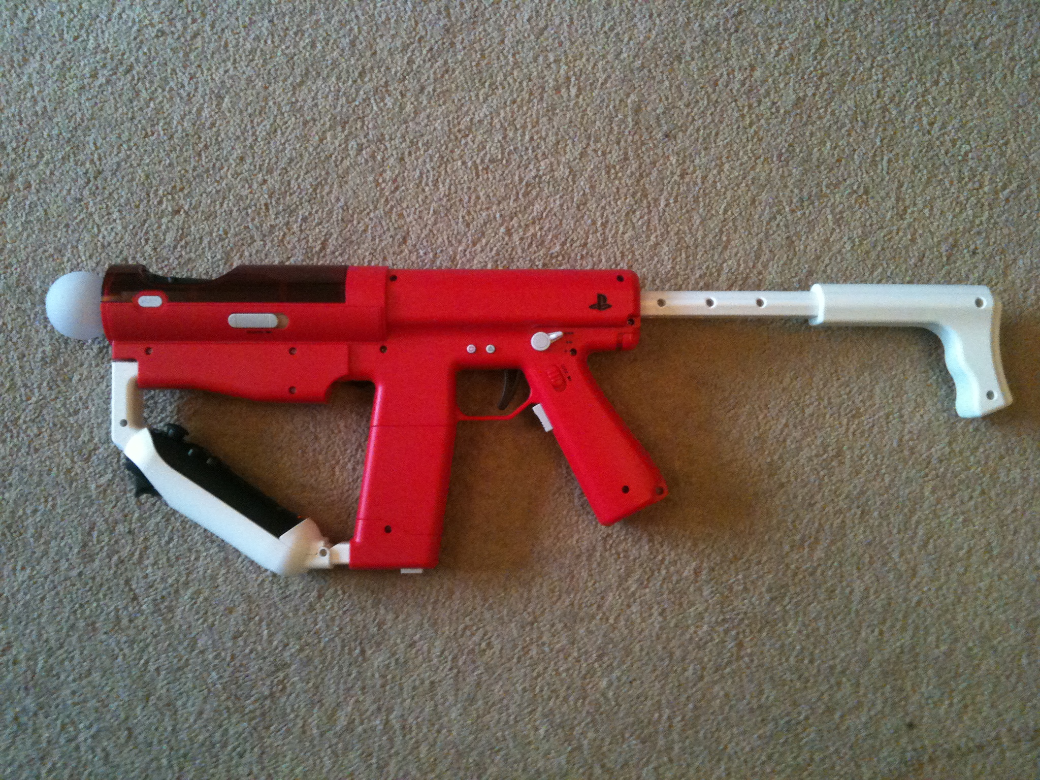 a red plastic toy gun laying on the floor