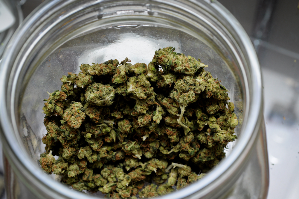 a glass jar filled with buds sitting on top of a counter