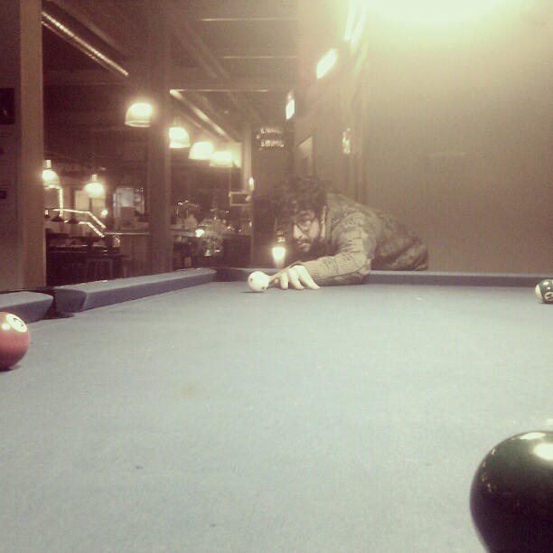 a person leans down to the side of a pool table