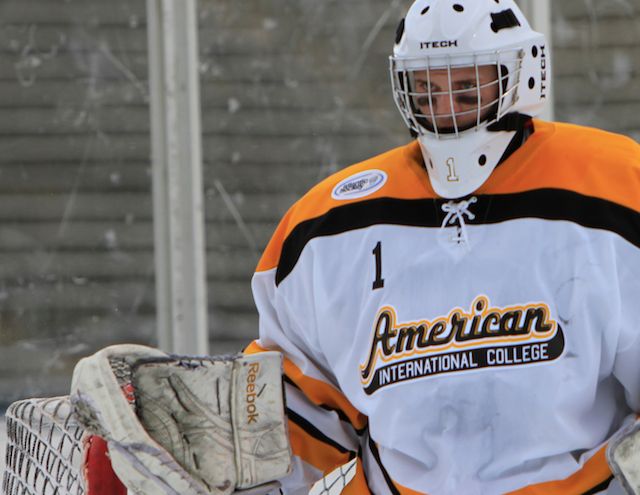a man in an orange and white jersey holding a hockey goalie's mitt
