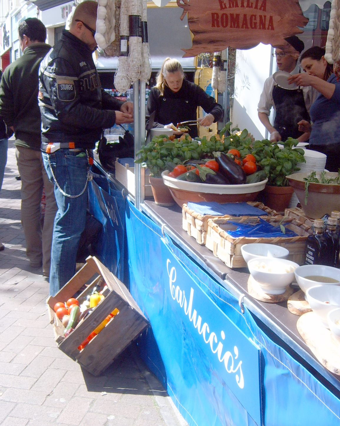 people gathered at a food stand with food on display