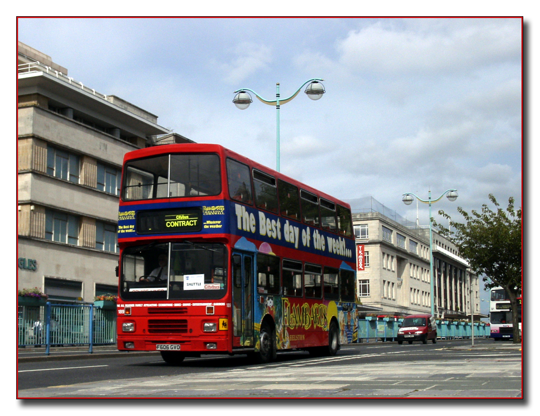 the double decker bus is traveling down the street