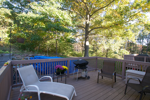 an outside deck with a table, chairs, and grill