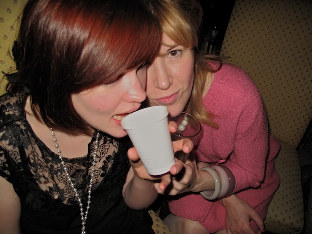 a woman with red hair blowing into a paper cup