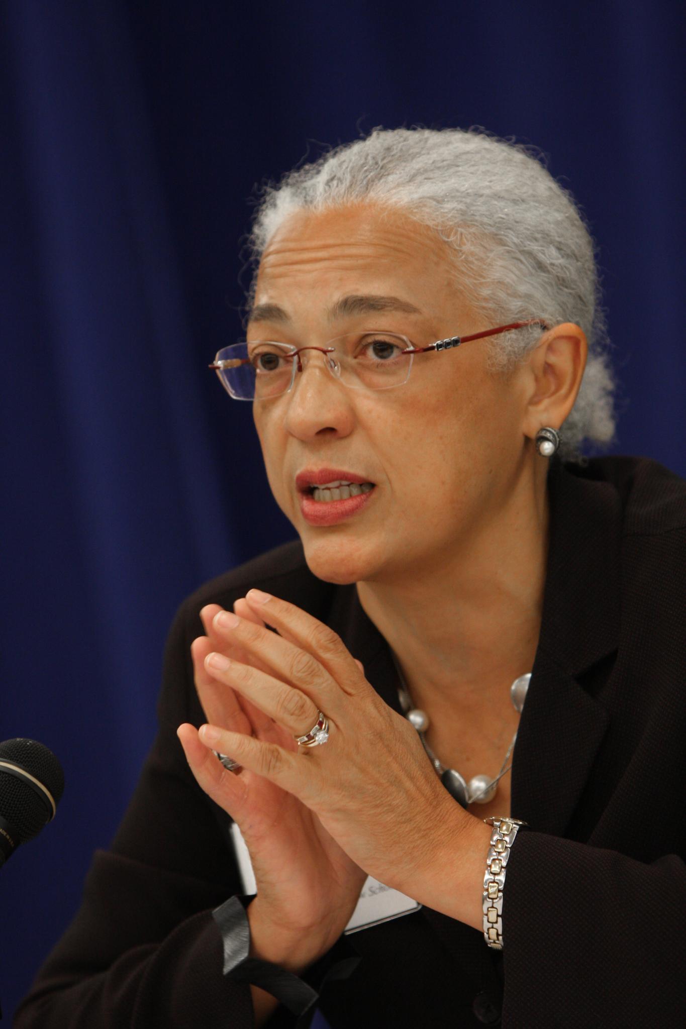 a lady wearing glasses talking at a microphone